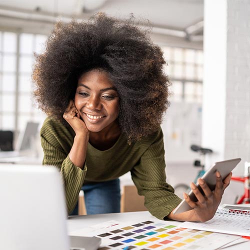 Happy woman holding a cell phone, in front of a laptop